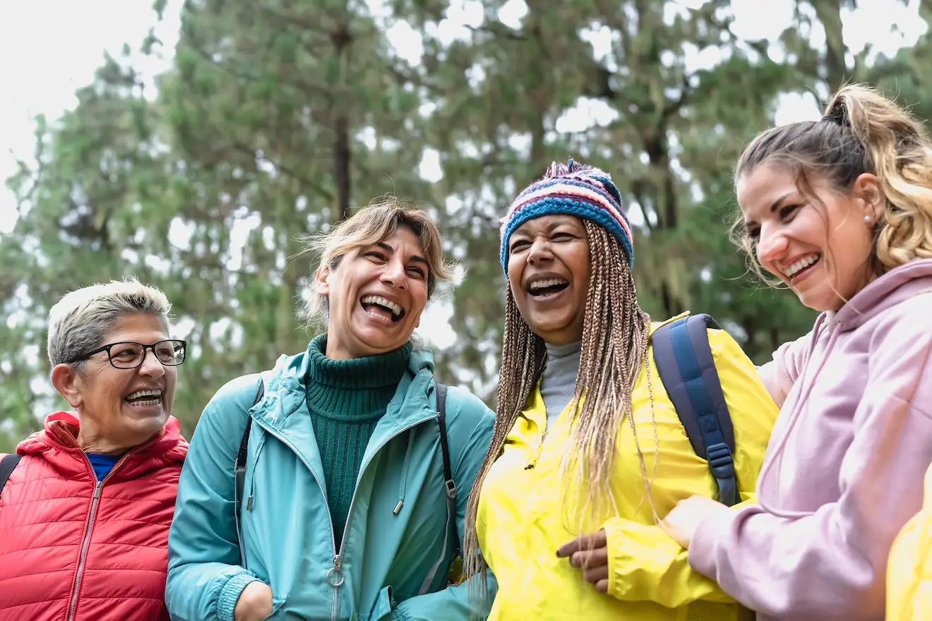 Friends of different ages laughing together in the woods