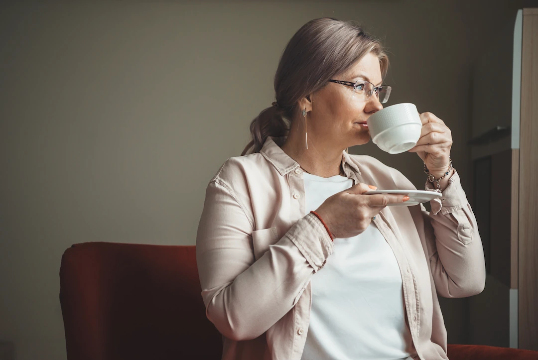 Senior woman drinking coffee and looking out window