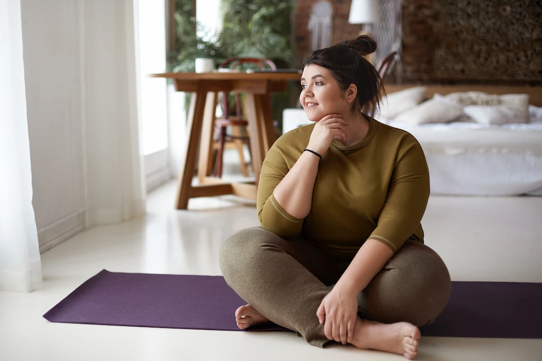 Young plus size woman sitting on yoga mat
