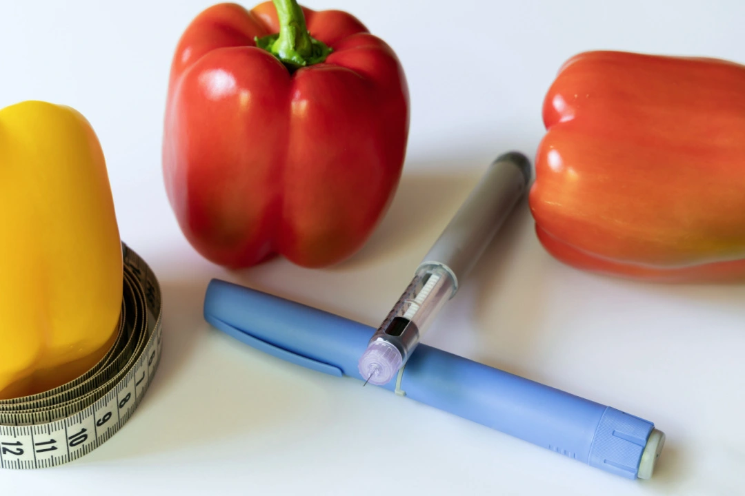 Injections pens laying beside measuring tape and healthy foods