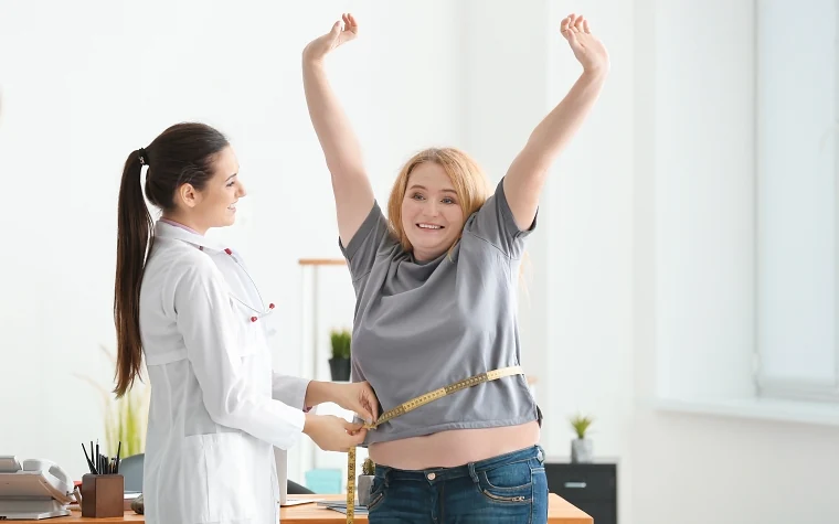 woman getting her waist measured by a doctor